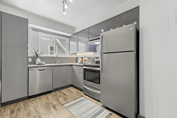 A modern kitchen with stainless steel appliances and wooden flooring.